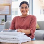 Cleaning, happy and laundry with portrait of woman in living room for housekeeping service, clothes